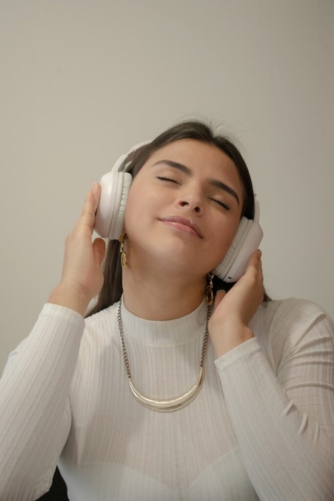 a woman with her eyes closed listening to soothing meditation music on headphones