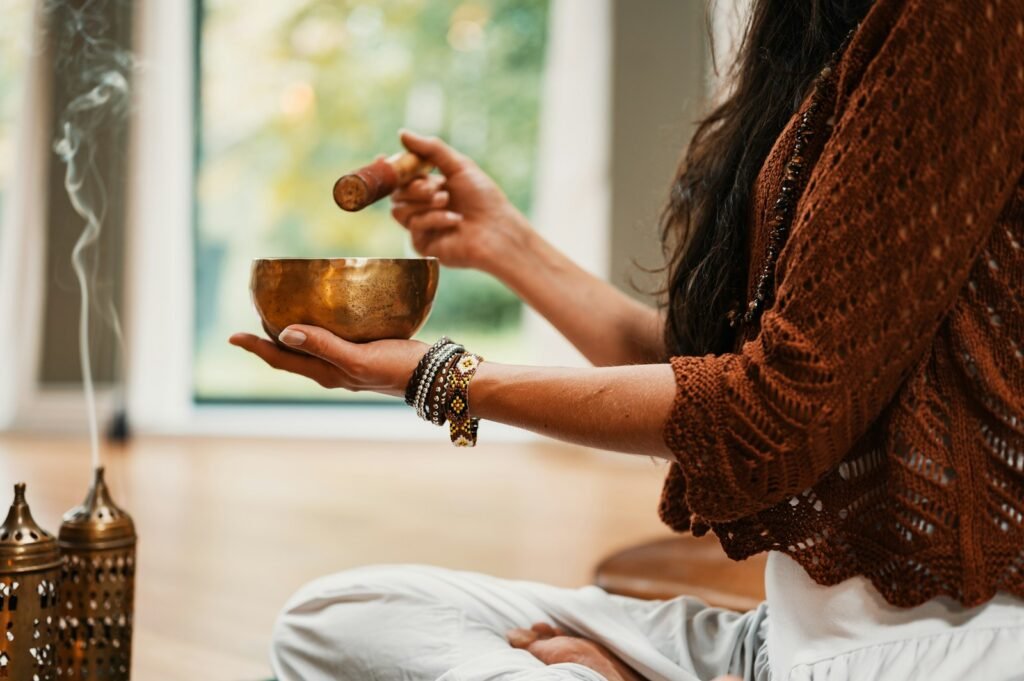 A woman in a brown sweater holding a singing bowl and the mallet used during a wondrous spectrum of meditation practices