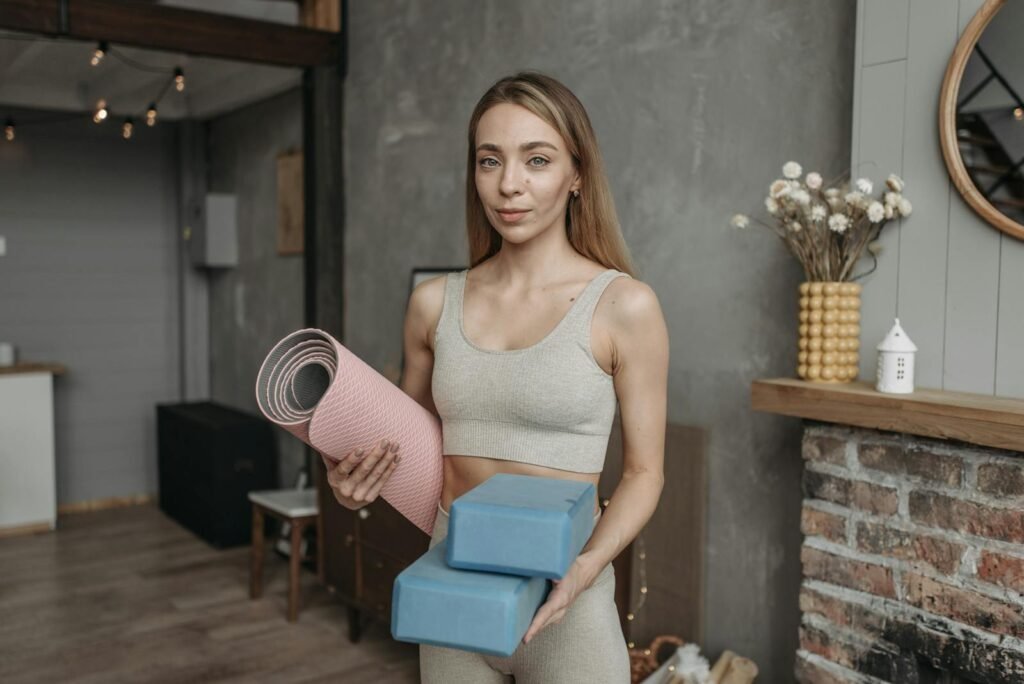 Woman Wearing a Gray Sports Bra Holding a Yoga Mat and Blocks