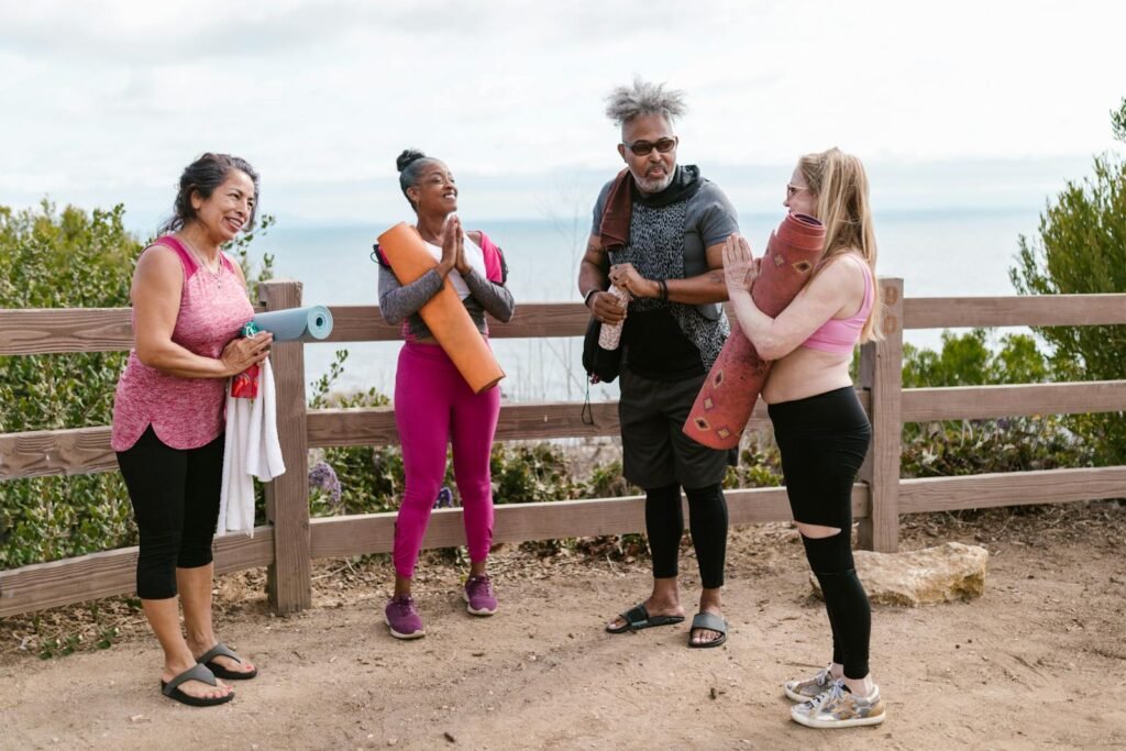 Three women and a man standing outside preparing for a yoga class with their restorative yoga props