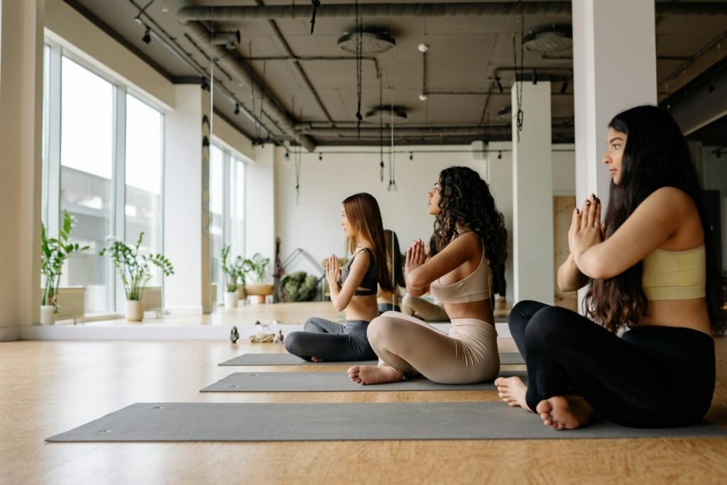 Three women sitting crossed-legged meditating in a yoga class