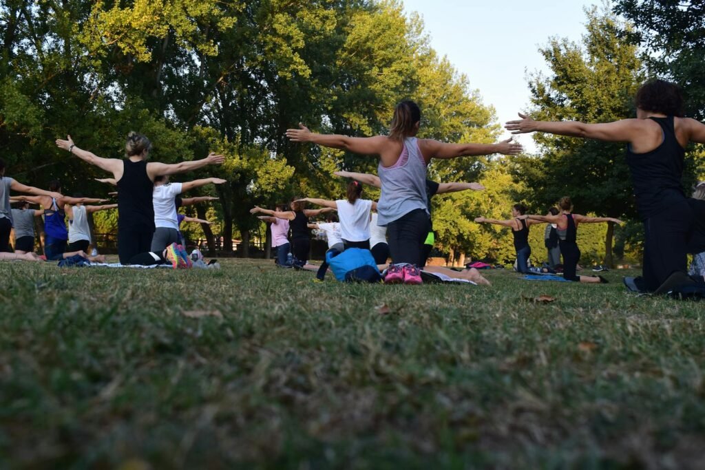 Several women performing yoga for anxiety on green grass near trees