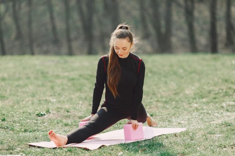 Flexible young women performing a gentle stretching with restorative yoga exercise in park