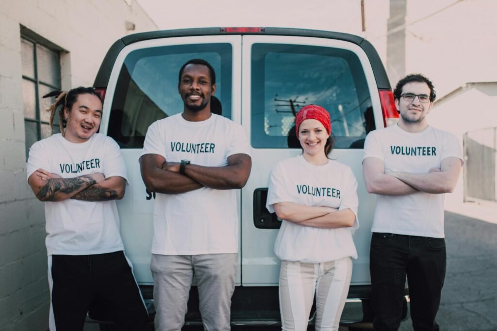 Three male and one female volunteers standing behind a white cargo van