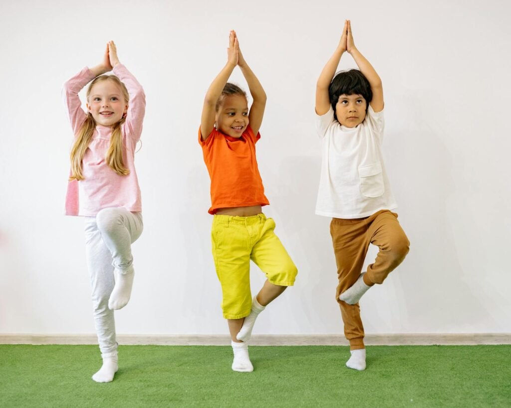 Three active children doing yoga poses for kids' balancing exercises