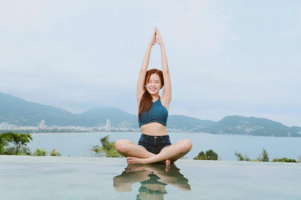 A woman doing yoga by the poolside