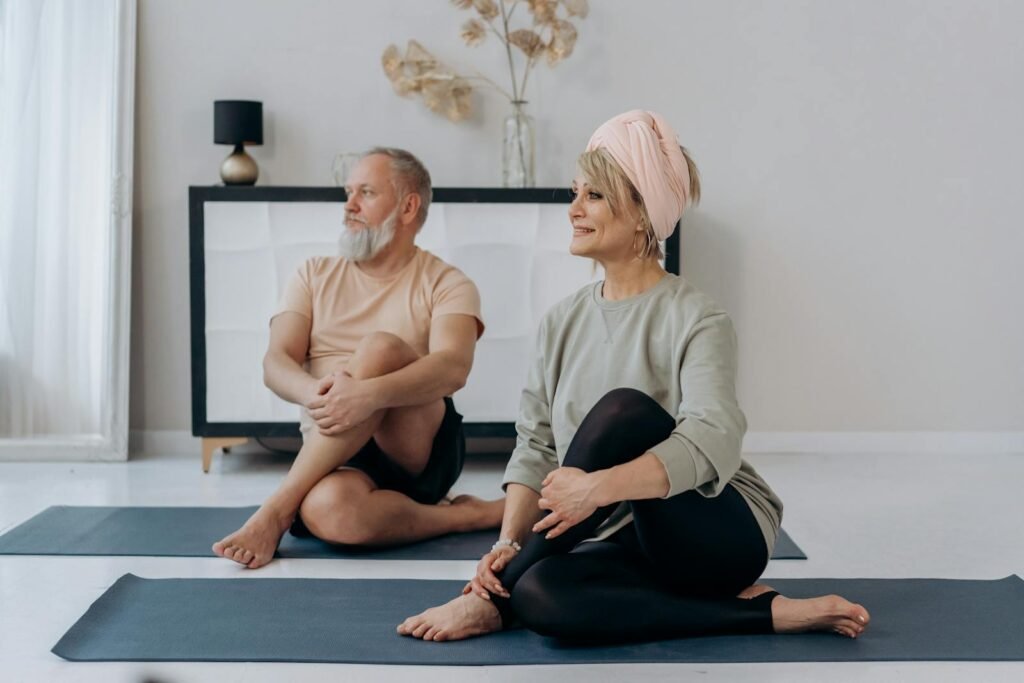 An elderly couple practicing yoga together to experience the amazing benefits of yoga