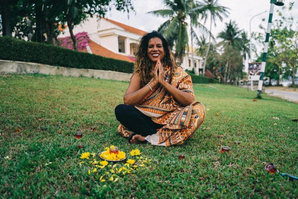 A smiling woman sitting crossed-legged on the grass